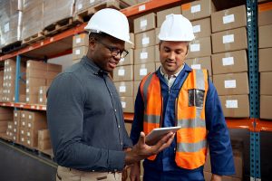 Project Manager and technician checking digital tablet at factory warehouse