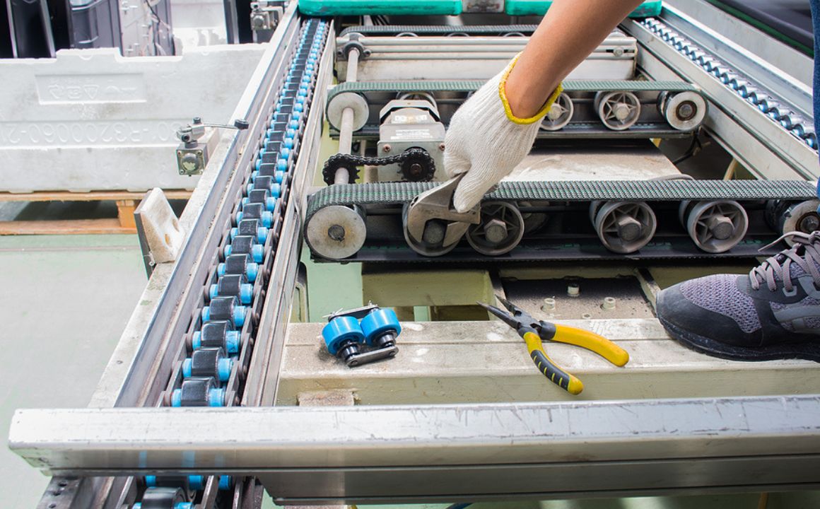 Factory Maintenance Technician Working On Conveyor