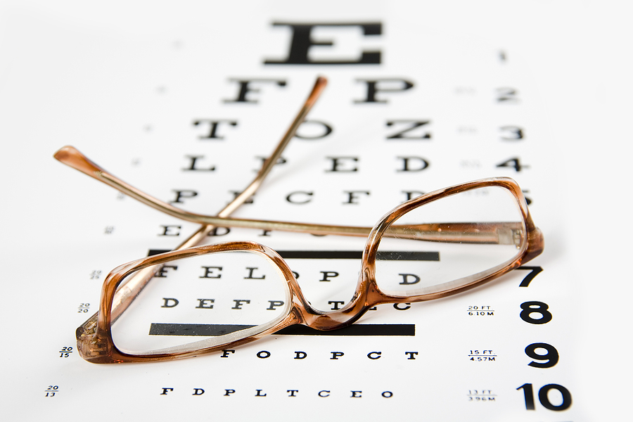 horn rim eyeglasses sittin on top of an exam chart forground sharp and background soft