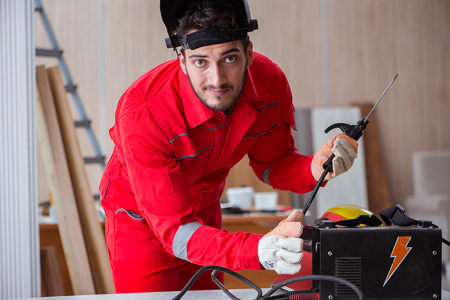 Young repairman with a welding gun electrode and a helmet preparing for his first day on the job